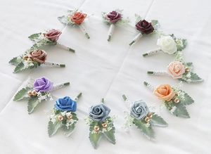 Detailed top view of twelve colorful artificial flower boutonnieres on white fabric