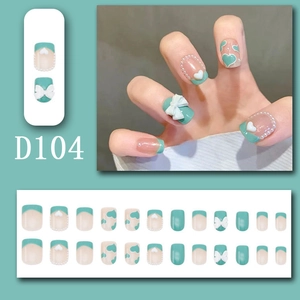 Detail of green press-on nails set with 3D white bows, heart patterns, and pearls