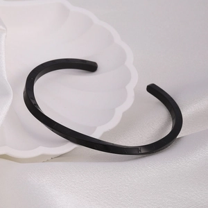Macro view of black Mobius cuff bracelet featuring engraved Roman numerals on a silk backdrop
