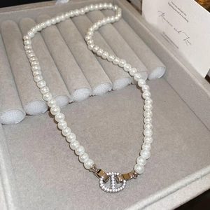 Détail d'un collier de perles blanches avec pendentif nez de porc serti de strass
