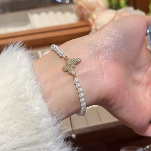 Close-up of pearl bracelet featuring a gold butterfly pendant with sparkling zircons