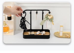 Detail of metal jewelry organizer with wooden base being used in a home vanity setting
