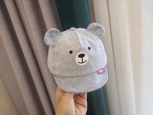 Close-up of baby sun hat with grey stripes, cute bear face embroidery and soft bear ears