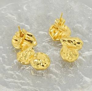 Macro shot of gold hammered petal earrings with irregular lava texture on crystal stone