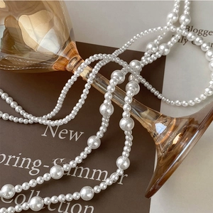 Artistic detail of layered white pearl necklace with amber glass and seasonal card