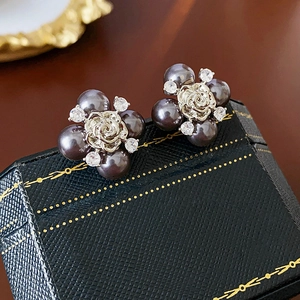 Macro view of grey pearl floral earrings with silver rose and zircon on jewelry box