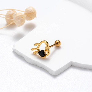 Macro shot of gold heart-shaped stud earring with black zircon and screw back closure