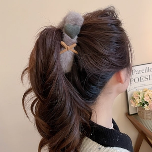 Detail view of the grey faux fur hair claw clip featuring a dark green heart and brown bow