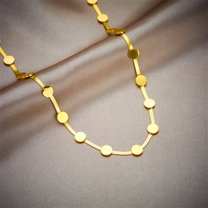 Elegant gold snake chain necklace with round flat discs on luxury silk fabric