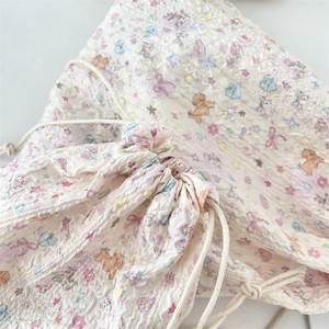 Macro shot of drawstring storage bag featuring cartoon floral patterns and seersucker texture