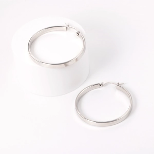 Close-up of classic minimalist silver stainless steel hoop earrings on white display stand