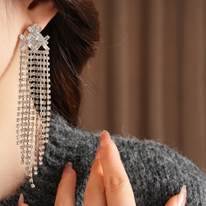 Primo piano di orecchini vintage in argento con nappe e zirconi indossati da una modella
