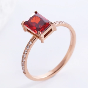 Rose gold princess ring with rectangular red zircon and small side diamonds on white back