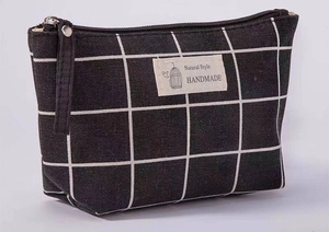 Detail showing checkered canvas makeup bag with Natural Style birdcage label and metal zipper