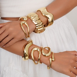 Elegant gold stacked bangles set with irregular minimalist designs on female arms