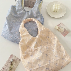 Détail des sacs cabas texturés bleu clair et beige avec des motifs de nœuds délicats