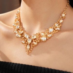 Close-up of champagne pear-cut crystal V-shaped necklace on model in warm light