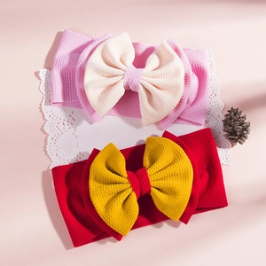 Close-up of two waffle-textured baby headbands with large bows on a lace background