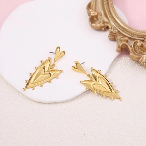 Detail of vintage gold double heart drop earrings on a white platform with pink background