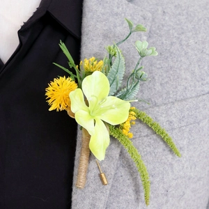 Green lily boutonniere with yellow poms and twine handle on a grey suit lapel