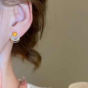 Detailed close-up of double golden rings with micro-inlaid crystals and an orange bead