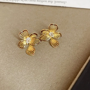 Macro shot of gold floral earrings with teardrop zircon on elegant book background