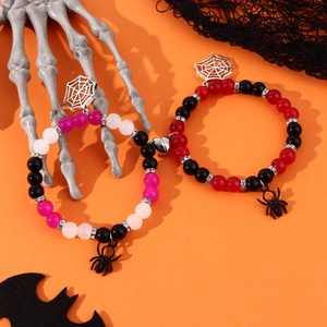 Detail of Halloween spider charm bracelets with magnetic heart clasps on orange background