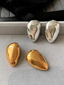 Polished gold and silver teardrop earrings on gray velvet display tray