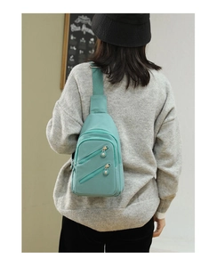 Detail view of teal nylon crossbody bag on model showing adjustable strap and multi-pocket design