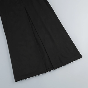 Detail of elegant black tube maxi dress featuring silver beaded hem and high slit fabric