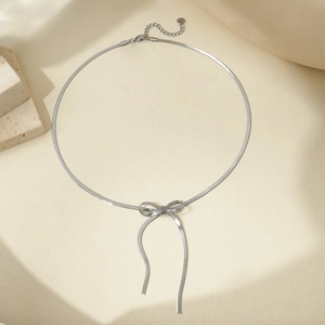 Close-up of silver bow pendant on flat snake bone chain with adjustable lobster clasp