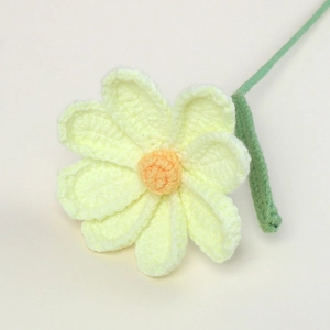 Detailed view of handmade crochet cosmos flower with yellow petals and green leaves