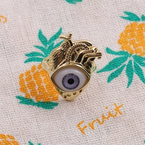 Detailed close-up of golden heart-shaped ring featuring a unique purple eye centerpiece