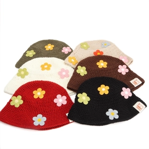 Detail of handmade knit crochet bucket hats with colorful flower patches and H labels