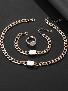 Detailed view of chunky golden chain jewelry set with white rectangular enamel charms