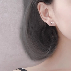 Elegant S999 silver bow earrings with long tassel chain shown on a female model