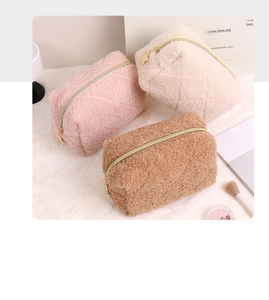 Close-up of quilted teddy fleece cosmetic bags in pink, cream, and brown with gold zippers