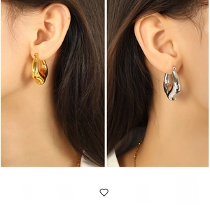 Detailed close-up of chunky gold and silver C-shape hoop earrings with a glossy finish