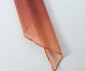 Dettaglio macro del tessuto a rete arancione sfumato e cuciture raffinate sul vestito