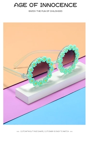 Detailed view of mint green flower round frame kids sunglasses on geometric stand