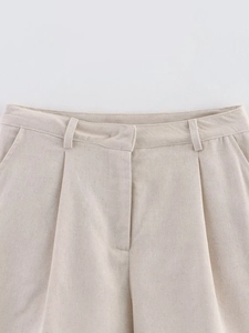 Close-up of oatmeal linen shorts waist details featuring pleats and textured fabric