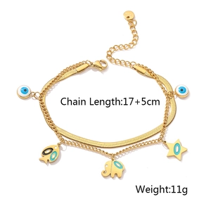 Detail of layered gold steel bracelet with evil eye, elephant, and fish charms
