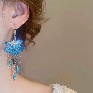 Close-up of fan-shaped blue crystal tassel earrings with sparkling zircon on a model