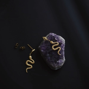 Detailed view of snake-shaped gold earrings with scale texture on natural amethyst stone