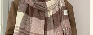 Close-up of brown plaid scarf showing soft knit texture and fringe details on a coat