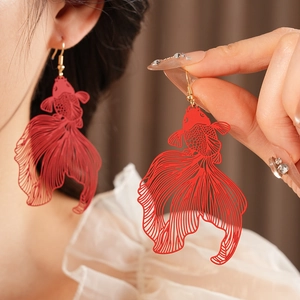 Détail de boucles d'oreilles carpe koï évidées rouges avec crochets dorés sur modèle