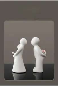 Detailed close-up of white ceramic abstract couple sculpture with matte finish and pink flower