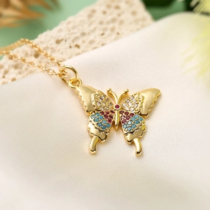 Gold plated butterfly pendant necklace with colorful zircons on beige silk fabric