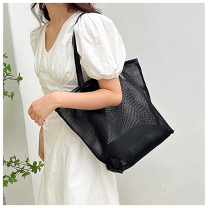 Model showing large black mesh tote bag with long straps for beach or daily use