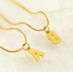 Detail of gold letter A and B pendants on sleek stainless steel snake chains